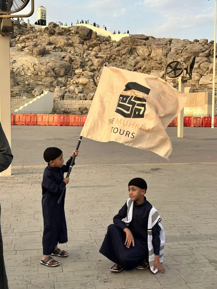 A young pilgrim holding the Muhrim flag below Jabal al-Rahmah at Arafat