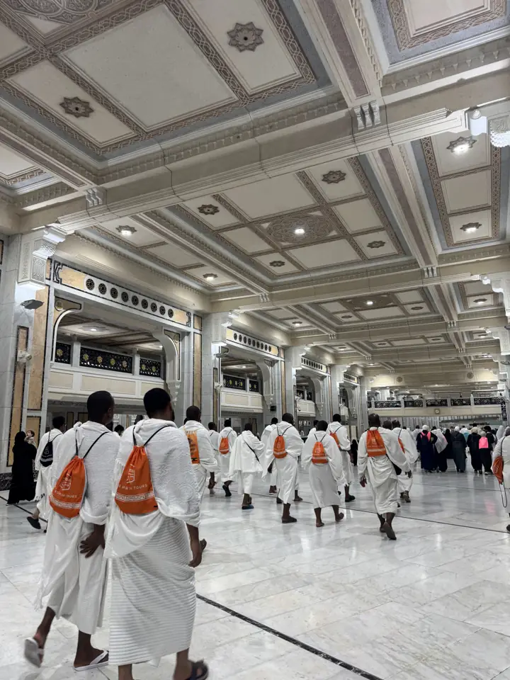 Pilgrims in ihram with orange Muhrim bags inside Masjid al-Haram