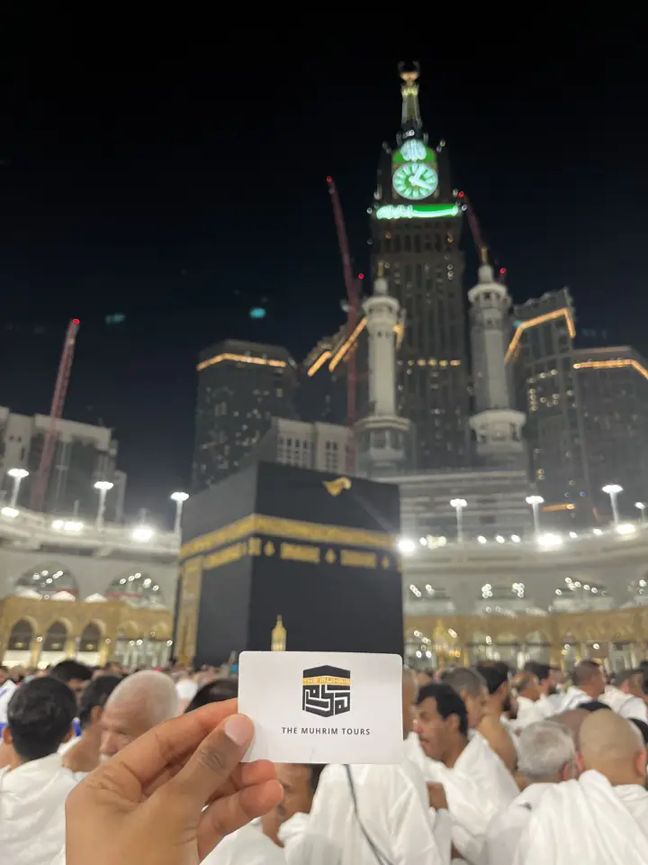 A Muhrim Tours card held up in front of the Kaaba